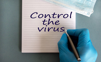 Male doctors hand in blue glove writes the words 'control the virus' on a white note. Medicine...