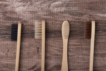 Top above overhead flat lay flatlay close up macro photo of four toothbrushes of black white beige and brown colors isolated on rustic wooden background