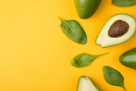 Top Above Overhead View Cropped Photo Of Cut Avocado And Baby Spinach Leaves Places To The Right Side Isolated On Yellow Background