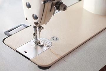 Needle presser foot with thread of white industrial sewing machine for sew cloth close-up.