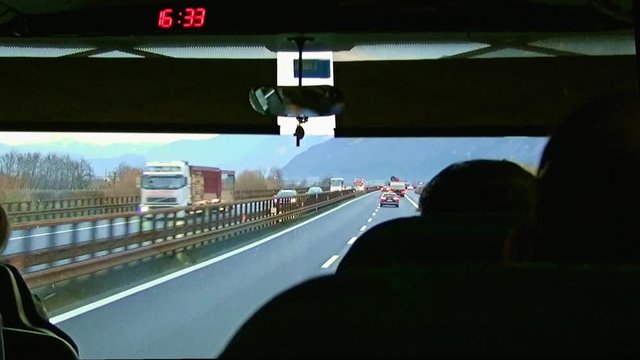 Video shot inside a tour bus behind the driver seat during a trip as traveling on a highway among the Alps,  Brenner pass, Italy-Austria border.
