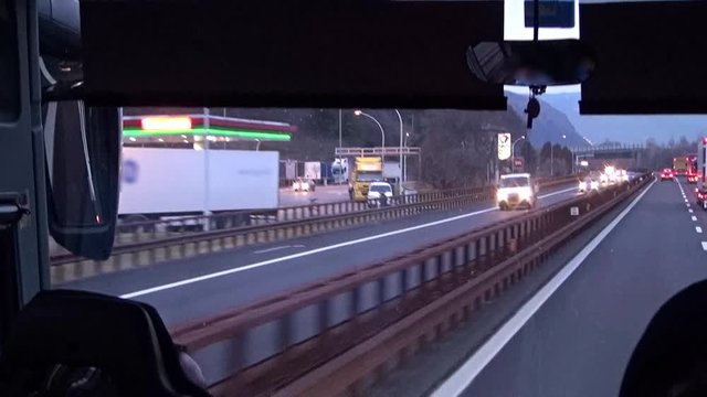 Video shot inside a tour bus behind the driver seat during a trip as traveling on a highway among the Alps,  Brenner pass, Italy-Austria border.
