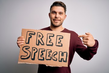 Young man with blue eyes holding banner on protest for free speech asking for free communication with surprise face pointing finger to himself