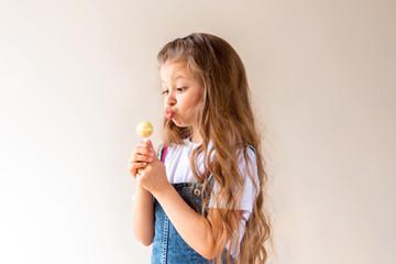 Cute little girl with long wavy hair and holding a Lollipop on a stick.