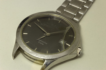 Broken wrist watch, with its glass shattered and damaged bracelet