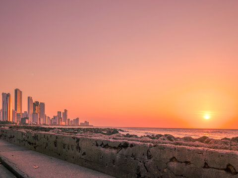 Scenic View Of Sea And Buildings Against Sky During Sunset