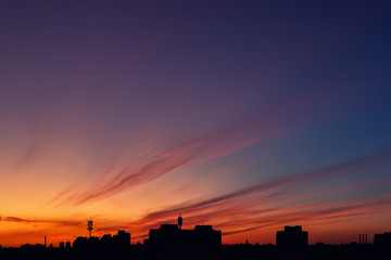 Dramatic colorful red purple to blue sunset or sunrise sky landscape with line row of city buildings silhouette . Natural beautiful cityscape dawn background wallpaper. Metropolis rise twilight time