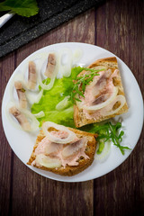 sandwich with salad, herring and herbs with onions in a plate