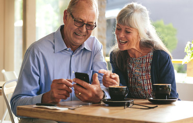 Senior couple using mobile phone at a cafe