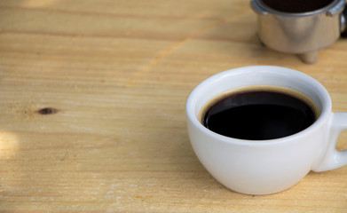 Black coffee in a white cup on natural color wooden table. Relaxing time, lifestyle concept.