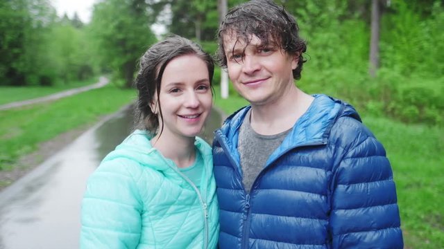 Portrait of the young couple standing in the park after the rain