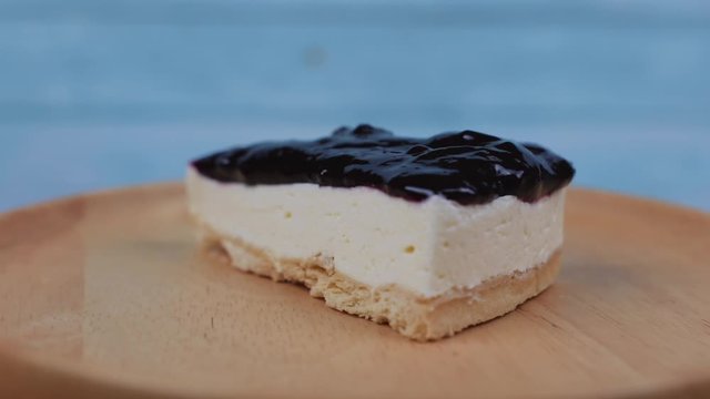Blueberries cheese cake on a wooden plate, rotating on a wooden plate