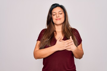 Young hispanic woman wearing casual t-shirt standing over isolated background smiling with hands on chest with closed eyes and grateful gesture on face. Health concept.