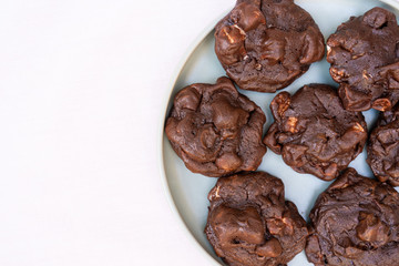 Baked dark chocolate cookies with marshmallow on light color plate, with white background, with copy space