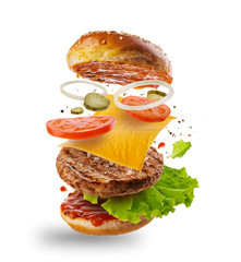Burger with flying elements. Delicious burger with flying ingredients isolated on white background. Flying Burger Slices. - obrazy, fototapety, plakaty