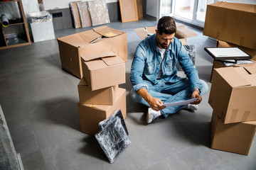 Cheerful young guy looking at flat layout inside