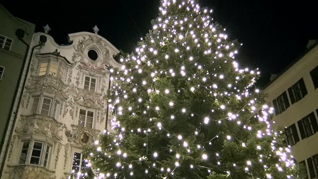 Lights turned on at night on a fir tree for Christmas in front of the Helbling House, Innsbruck, Austria.