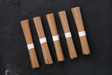 Dry soba buckwheat noodles on black background