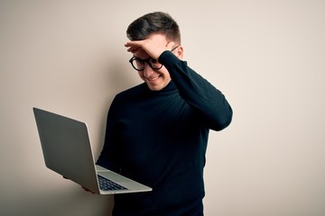 Young handsome caucasian business man wearing glasses using computer laptop stressed with hand on head, shocked with shame and surprise face, angry and frustrated. Fear and upset for mistake.