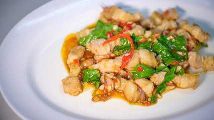 Close up and selective focus of delicious yummy tasty traditional Thai style food hot and spicy stir-fried with pork and basil on white plate , popular food in Thailand.