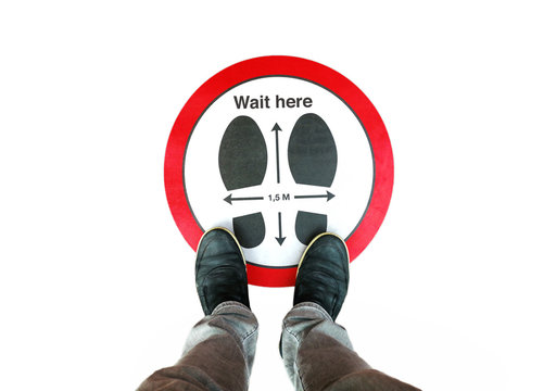 A person standing on a social distancing sign