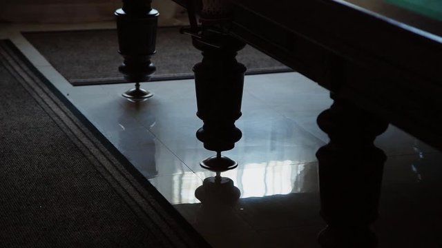 The legs of the pool table in the backlight are on the tiled floor