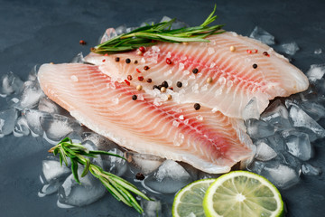 Fresh fish fillet of sea bass in ice on a dark slate background.