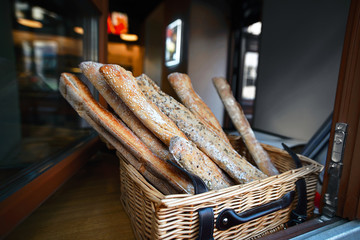 French bread baguettes at bakery window display. Wicker basket full of fresh baked bread, tasty delicious crusty bread. Bread baguettes in basket at baking shop