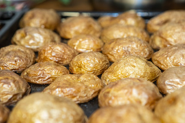 Hot baked potatoes with peel in a platter taken out of the oven. Selective focus, macro photography