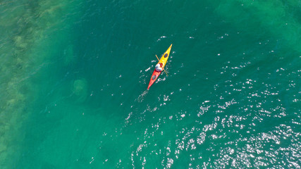 Aerial drone photo of fit athlete rowing with his canoe exploring an exotic destination island