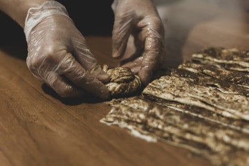 Hands of a woman making dough with plastic gloves on the table