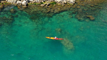 Aerial drone photo of fit athlete rowing with his canoe exploring an exotic destination island