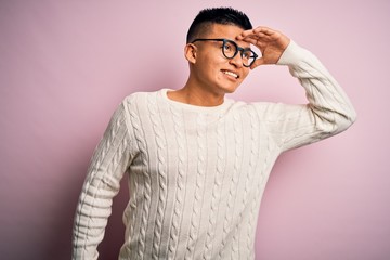 Young handsome latin man wearing white casual sweater and glasses over pink background very happy...