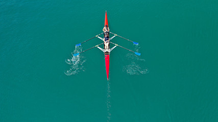 Aerial drone photo of athlete competing in canoe race in tropical lake with emerald waters