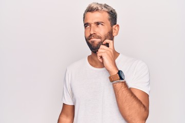 Young handsome blond man wearing casual t-shirt standing over isolated white background thinking...