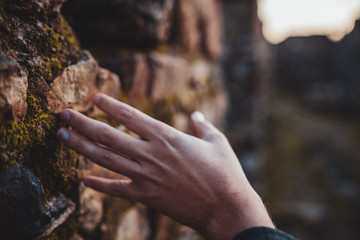 mano acariciando las piedras de una pared de un castillo medieval destruído