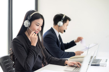 Two staff at the customer service call center. Operator in headphones with microphone consulting client on laptop in customer support service.