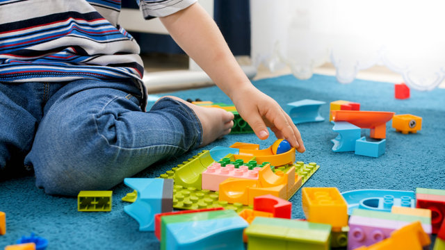 Closeup image of little toddler boy assembling track for marble run game