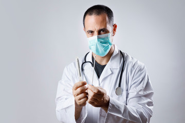 medico con camice bianco e mascherina chirurgica tiene in mano un tampone faringeo per rilevare il...