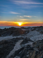 P&ocirc;r-do-sol na praia com rochas