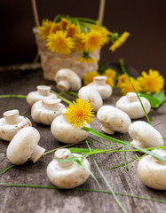Champignons in a basket and yellow dandelions on a wooden rustic table