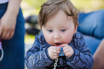 little one year old boy playing with his parents in the woods. portrait of a little curly boy with a pacifier