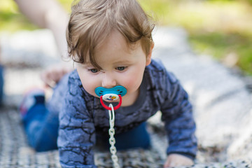 little one-year-old boy climbs in the woods. child explores the forest. curly boy with a pacifier...