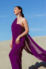 Fototapeta na wymiar Amazing beautiful brunette woman with the Peacock feather in purple fabric in the desert. Oriental, indian, fashion, style concept