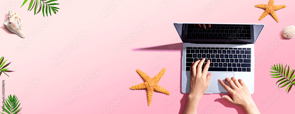 Poster person using a laptop computer with summer theme objects - flat lay