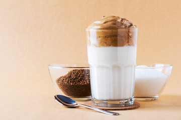 Dalgon's whipped coffee in a glass Cup on a white wooden background. Next to the ingredients for making a Korean refreshing coffee drink.