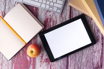 digital tablet with white screen , books and apple on table 