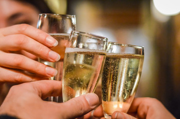 Hands and glasses of toasting friends with rose champagne close up