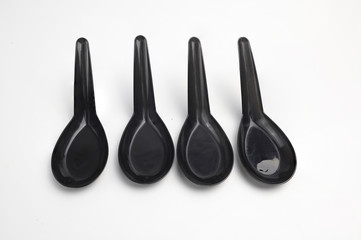 Black plastic spoons arranged on a white background
