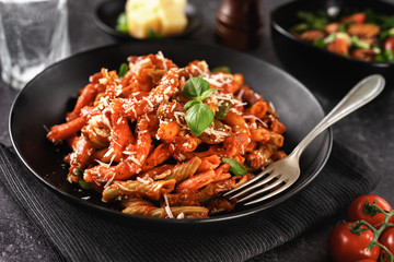 Close up of delicious tomato pasta penne on black background